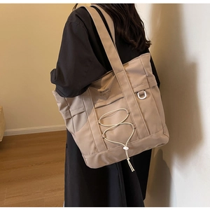 Dettaglio della borsa tote in nylon kaki con coulisse bianche vista su modella