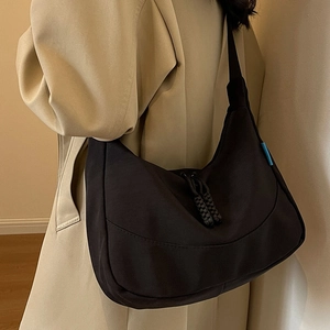 Black large capacity nylon hobo bag shown on model with woven zipper pull details
