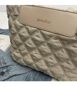 Detailed close-up of quilted khaki tote bag with leather flap and gold brand lettering