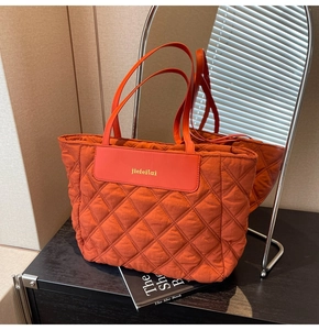 Detail of caramel quilted tote bag featuring golden brand logo on a smooth leather patch