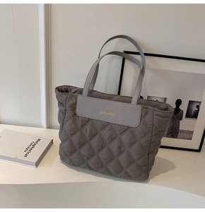 Detailed view of the diamond quilted texture and gold logo on the grey tote bag