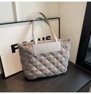 Detail of grey quilted tote bag with diamond stitching and brand logo leather patch
