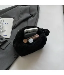 Intérieur spacieux du sac en peluche noir contenant téléphones, portefeuille et cosmétiques