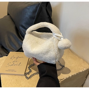 Détail du sac oreiller en laine d'agneau blanche avec pompon et bandoulière argentée