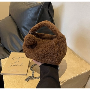 Détail du sac polochon en peluche marron avec bandoulière chaîne et pompon décoratif