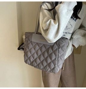 Detail of grey quilted tote bag with diamond stitching and golden brand label