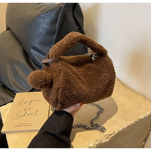 Détail d'un sac oreiller en peluche marron avec fausse fourrure et chaîne en métal argenté