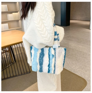 Detailaufnahme der großen blau-weiß gestreiften Plüsch-Tragetasche von einem Modell gehalten