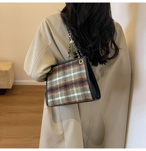 Dettaglio borsa tote a scacchi con catena dorata indossata su un trench color kaki