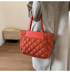 Detail showing the red-brown quilted tote bag with diamond pattern and brand patch