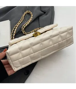 Detail of beige quilted texture and gold clasp on a crossbody chain bag