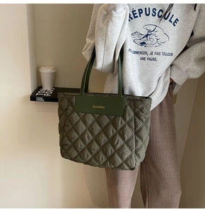 Detail of olive green quilted tote bag with leather logo patch and padded handles