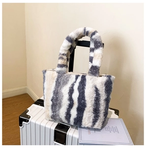 Detail der flauschigen Zebra-Einkaufstasche mit weichen Griffen auf einem Vintage-Koffer