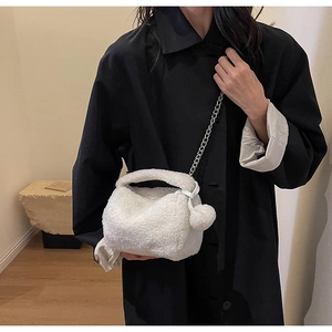 Détail d'un sac oreiller en peluche blanche avec chaîne argentée et pompon doux assorti
