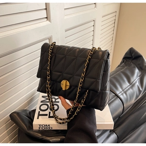 Detail of black quilted leather shoulder bag with gold chain and circular metal lock