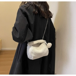Détail du sac à main en peluche blanche avec bandoulière chaîne et pompon doux