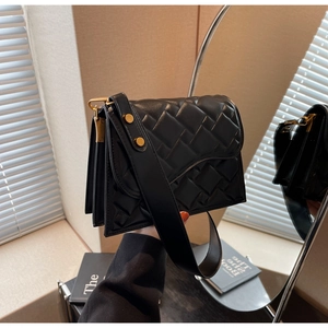 Dettaglio della trama trapuntata nera e fibbia dorata su una borsa a tracolla alla moda