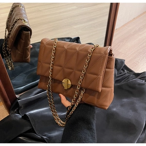 Detail of dark brown quilted leather bag with vintage gold chain strap and turn-lock