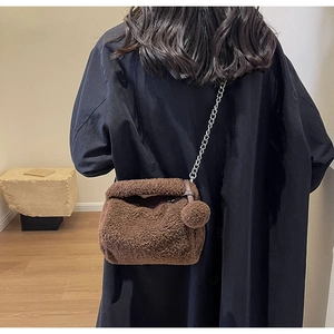 Vue détaillée du sac bandoulière en peluche marron avec chaîne argentée et pompon