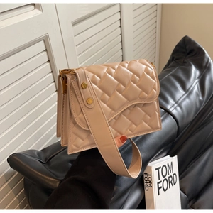 Dettaglio borsa a tracolla trapuntata beige con borchie dorate e tracolla larga su pelle