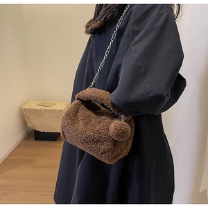Détail du sac polochon en peluche marron avec bandoulière chaîne et pompon doux