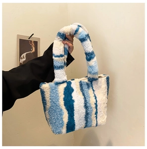 Detail der weichen, blau-weißen Plüschtasche mit Marmormuster, von einem Model gehalten