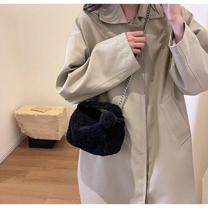 Détail du sac bandoulière noir en fausse fourrure avec chaîne argentée et pompon décoratif