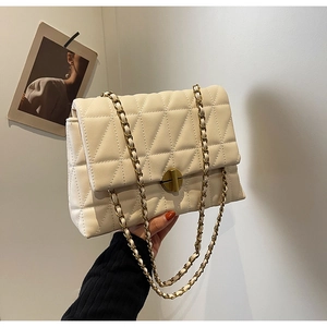 Detail of cream quilted chain bag with gold circular twist lock and leather metal strap