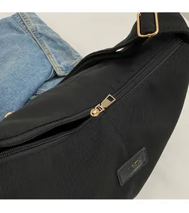 Detail of golden metal zipper and brand logo on black nylon crossbody dumpling bag
