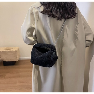 Détail d'un sac à bandoulière noir en fausse fourrure avec chaîne argentée et pompon