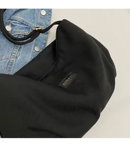 Detail of black corduroy shoulder bag with leather logo patch and gold lettering