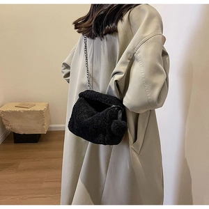 Détail du sac bandoulière noir en peluche avec chaîne argentée et pompon décoratif