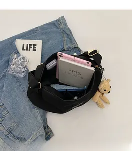 Spacious interior of black nylon crossbody bag with laptop, book and umbrella