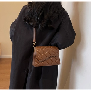 Dettaglio di una borsa a tracolla marrone con texture trapuntata e dettagli dorati