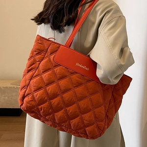 Quilted brick red tote bag with diamond pattern shown on model for daily commuting