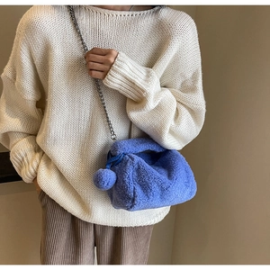 Détail d'un sac oreiller en peluche bleu vif avec bandoulière chaîne et pompon assorti