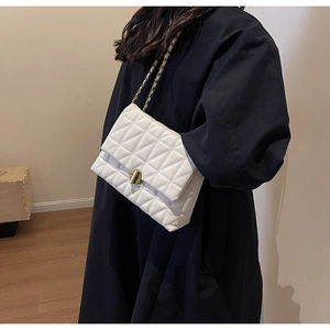 Close-up of a white quilted crossbody bag with a gold twist lock and metal chain strap