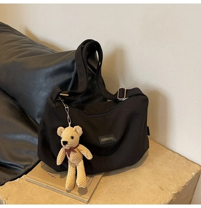 Detail of black nylon bag texture with luxury leather logo and cute teddy bear charm
