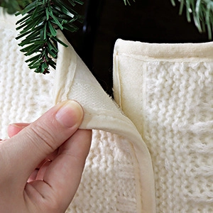 Detail of white cable knit Christmas tree skirt featuring hook-and-loop closure design