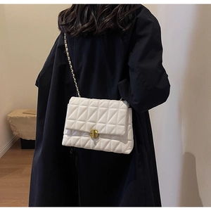Detail of white quilted handbag with golden chain strap and rotary buckle on black coat