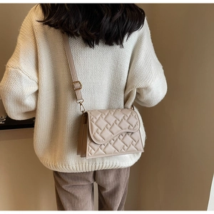 Dettaglio della mini borsa a tracolla trapuntata beige con patta asimmetrica e tracolla regolabile