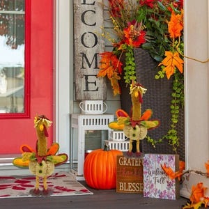 Detailed porch display of plush Thanksgiving turkey figurines with pumpkins and maple leaves