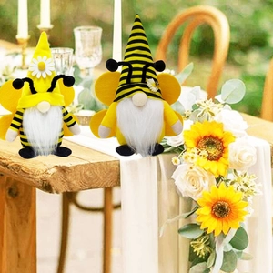 Detail of bee gnomes with yellow stripes and sunflower decor on a wooden garden table