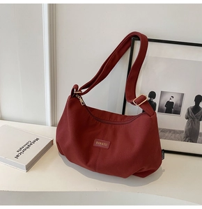 Close-up of wine red nylon crossbody bag with adjustable strap and brand tag detail
