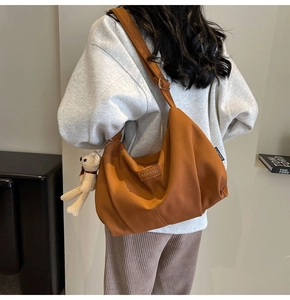 Close-up of caramel nylon dumpling bag with pleated texture and plush bear charm