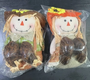Detail of harvest scarecrow dolls with hay hair and sunflower hats in clear packaging