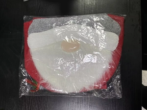 Detail view of red velvet Santa Claus toilet cover with plush beard in plastic packaging