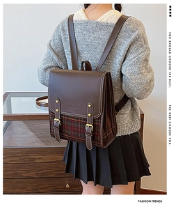 Detail of vintage plaid and brown leather backpack on female model in a retro setting