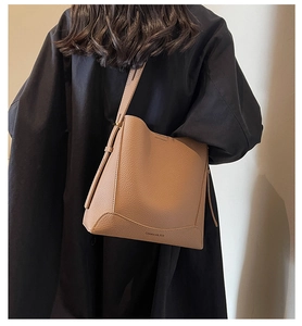Detailed texture of caramel pebbled leather tote with embossed logo and wide strap