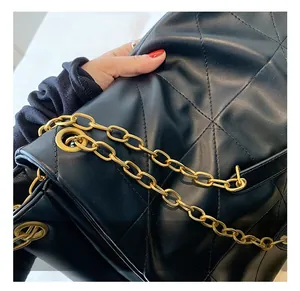 Detail of a black quilted tote bag featuring golden chain straps and premium hardware